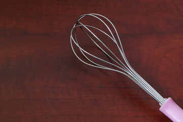Whisk on wooden background