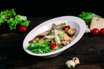 Caesar salad in a white plate on a wooden table