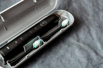 Modern black sonic or electric toothbrush in travel case on background with copy space. Concept of...