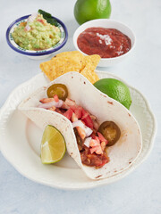 mexican taco on plate with lime, sauces and nachos