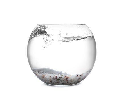 Splash of water in round fish bowl with decorative pebbles on white background