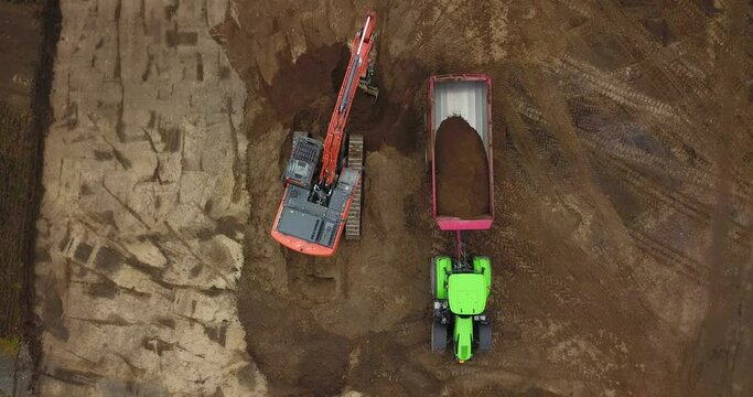 Bagger verl&auml;dt Erde auf einen Muldenkipper, Baustelle aus der Vogelperspektive