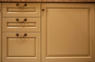 Fragment of cream drawers in classic style in warm light