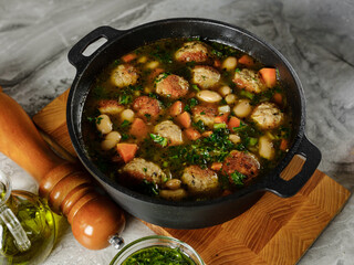 Cooking homemade soup with meatballs cutlets and vegetables in big pot on home kitchen background with ingredients. Copy space, closeup. Healthy food recipe book concept