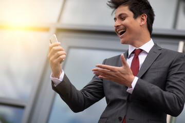 a smiling businessman looking at his cellphone outdoors