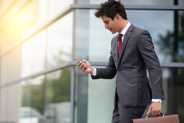 a businessman in a hurry, holding and looking at his cellphone outdoors