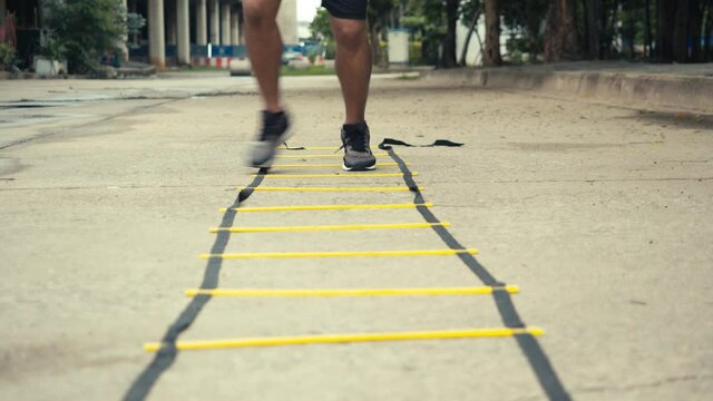 Close-up foot sportsman training with agility ladder equipment. athlete exercise training outdoors in the public park concept.