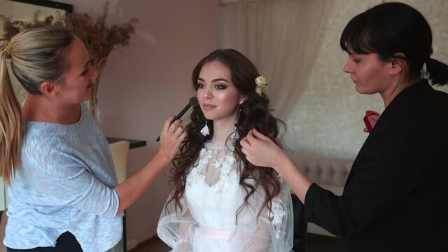 Makeup artist and hairdresser work on the image of the model.