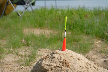 Fototapeta premium Fishing float in the sand on the lake. Fishing background.