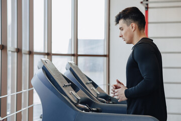 Fototapeta premium stylish guy in the gym is training on the treadmill. Healthy Lifestyle.