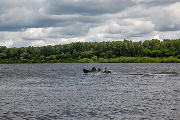 Fototapeta na wymiar three in a boat sailing on a river on a cloudy day