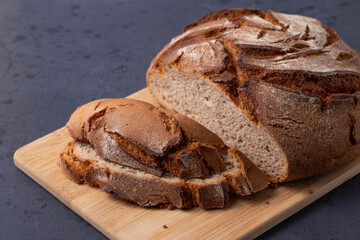 round single loan of brown bread on the stone concrete dark grey background