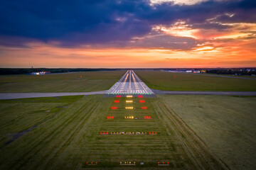 Aerial view on empty airport runaway with markings for landings and all navigation lights (ILS Cat II) on at the colorful sunset, clear for airplane landing or taking off in Wroclaw airport