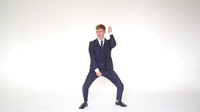 Business winners. A happy young man in formalwear celebrates, gestures, dances and expresses positivity. Isolated on white. Funny business man dancing and jumping with happiness