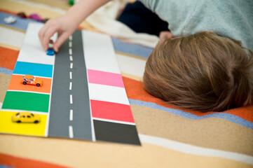 Boy sorting machines by color. Montessori concept, early education. easy ideas to do at home. kinder surprise cars on colored paper.