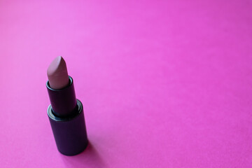 Close up of color nude lipstick on a pink background. Copy space and make up concept