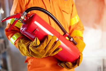 Fireman hand holding fire extinguisher. available in emergencies conflagration damage background. Safety concept. - obrazy, fototapety, plakaty