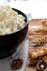 Healthy food: homemade cheese in a black round plate stands on a wooden table next to a jar of honey