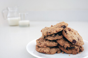 Plate of chocolate chip cookies with pitcher and glass of milk - background