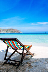 Beach chairs on a sandy beach by the ocean, the concept of relaxation, traveling on a tropical island, relaxation with beautiful views of the bruise sea and blue sky