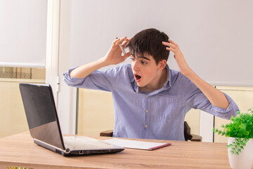 amazed or scared teenage student at desk with computer