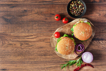 Beef burger with fresh salad, cheese, tomatoes and pepper spice on wooden background.