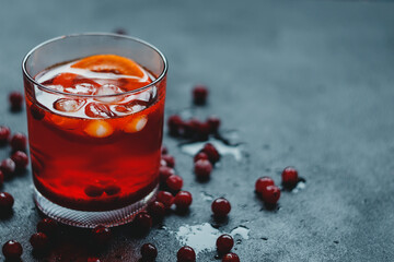 Aperol Spritz with ice and cranberries on a black background.