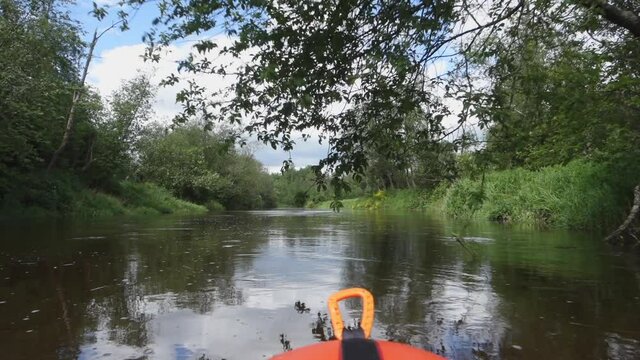River rafting in summer. Packrafting in wilderness. First person view from a packraft of river bank with forest. Derzha River, Tver Region, Russia.