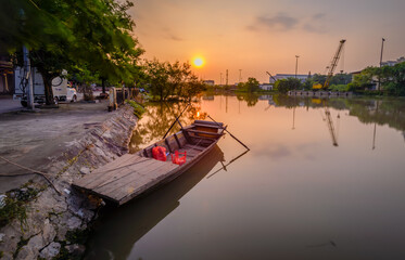 Fototapeta na wymiar Hai Phong, Viet Nam 2017 Beautiful sunset at Tam Bac river bank with the wood boat and perfect reflection