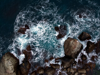 View from the height of the waves breaking on the rocks and white foam