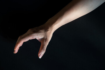 Fototapeta premium Reaching hand on black background, Right hand of Asian woman, Dark tone