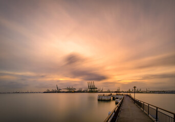 Fototapeta na wymiar Long cranes and view over the Singapore port, habour front during sunrise 