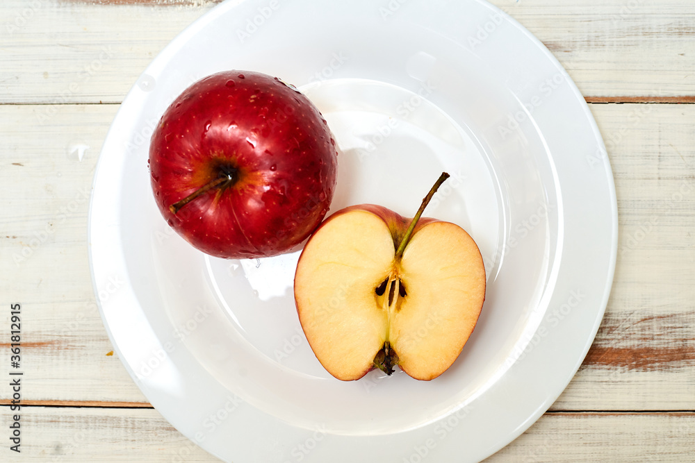 Poster Ripe red apples on a plate on a wooden background. - Posters