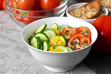 Ceramic bowl of tomato and cucumber salad on table