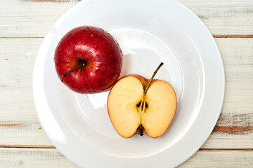 Ripe red apples on a plate on a wooden background.