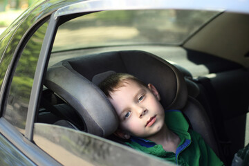 Fototapeta na wymiar The boy is hot in the car. The child is tired during the trip.