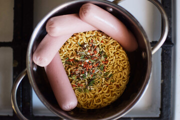 Instant vermicelli and sausages in a pan. Trashy, unhealthy food.