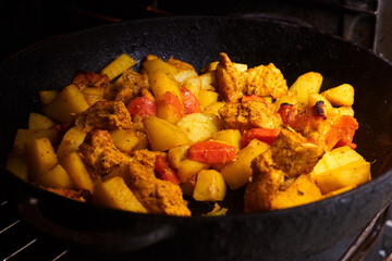 Stewed potatoes with vegetables in a pan in the oven.