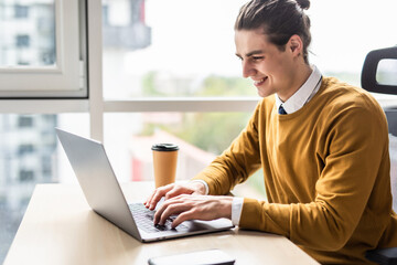 Young businessman in formalwear typing on laptop in modern office