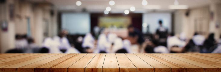 Panoramic empty clean wood counter table top on blur student study in classroom white light...