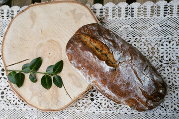 Frisches Sauerteigbrot auf einem Tisch mit Häkeldecke und einer Vase
