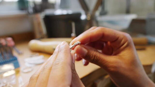 Close up of female jeweller measuring handmade ring on gauge in studio - shot in slow motion 