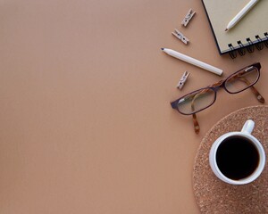 Empty office, blogger desk with place for text, dark brown background with copy space, glasses, cup of coffee, office supplies, styled stock photography.