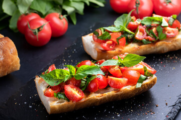 Homemade bruschetta with cherry tomatoes and basil closeup on a slate board. Italian cuisine. Antipasti. Vegan food