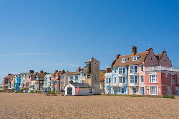 View of pastel coloured buildings on Crag Path facing Aldeburgh Beach on a sunny day with blue sky....
