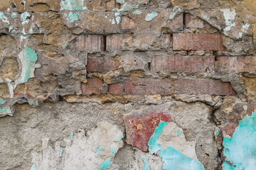 an old brick wall under a layer of broken plaster