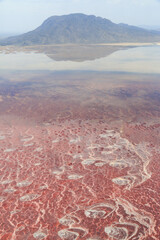 Aerial view of the salt pan and mineral crust with red algae of Lake Natron, in the Great Rift Valley, on the border between Kenya and Tanzania. The Rift Valley contains a chain of active volcanoes.