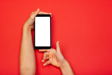 Smart phone in child's hands on the red background. The concept of digital, necessary things of a...