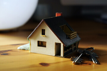 A miniature house and keys lying on a table 