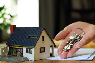 real estate concept - miniature house and hand holding keys